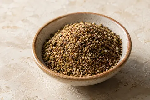 Mélange zaatar en poudre dans une coupelle artisanale, avec une texture d’herbes et de sésame